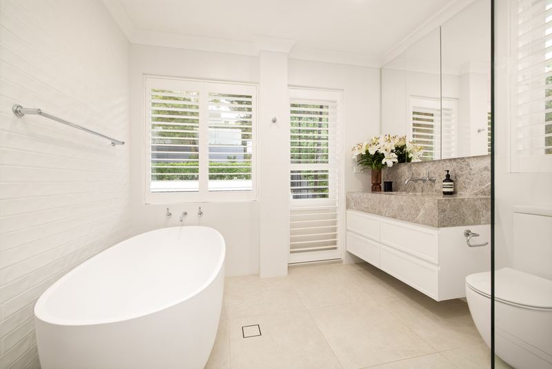 Bathroom with freestanding bath, stone vanity and plantation shutters